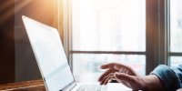 Close-up photo of male hands with laptop, freelancer at work